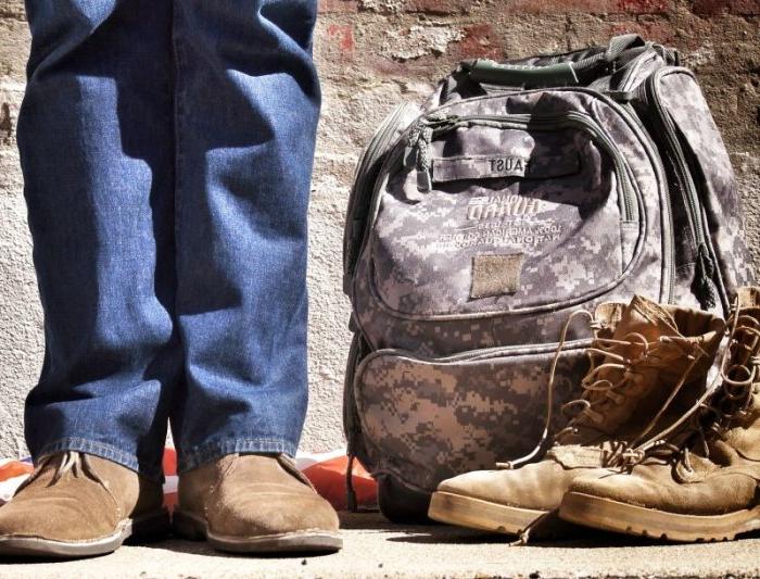 a military veteran standing next to books and backpack